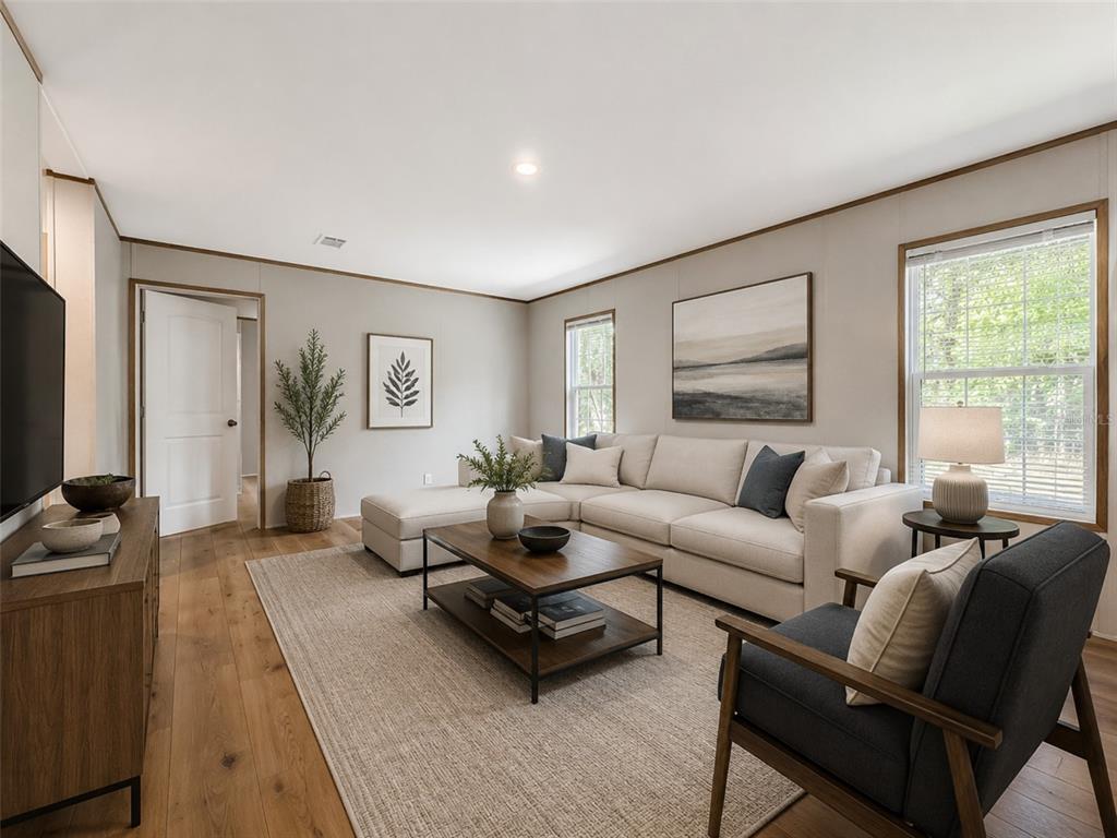 A living room features a sectional sofa, an armchair, a coffee table, and wood flooring — 115 BETSY ROSS PLACE, SATSUMA, FL
