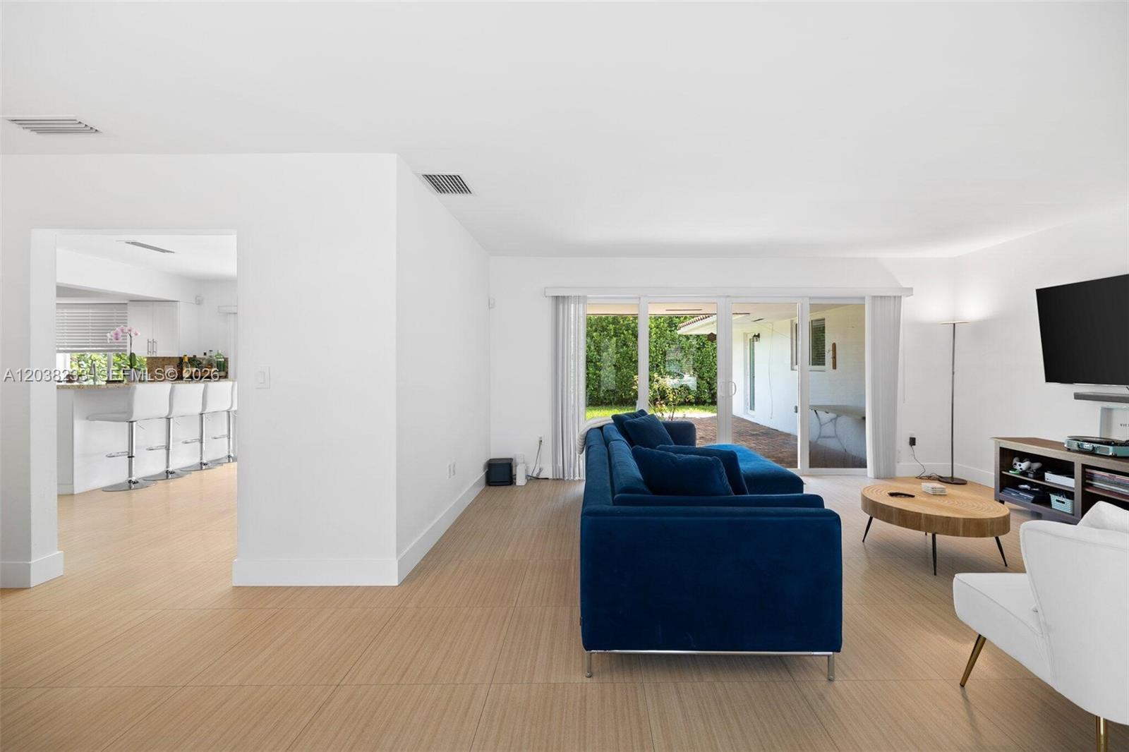 A living room with a blue sectional sofa, wood coffee table, and sliding glass doors — 811 Capri St, Coral Gables FL 33134, CORAL GABLES, FL