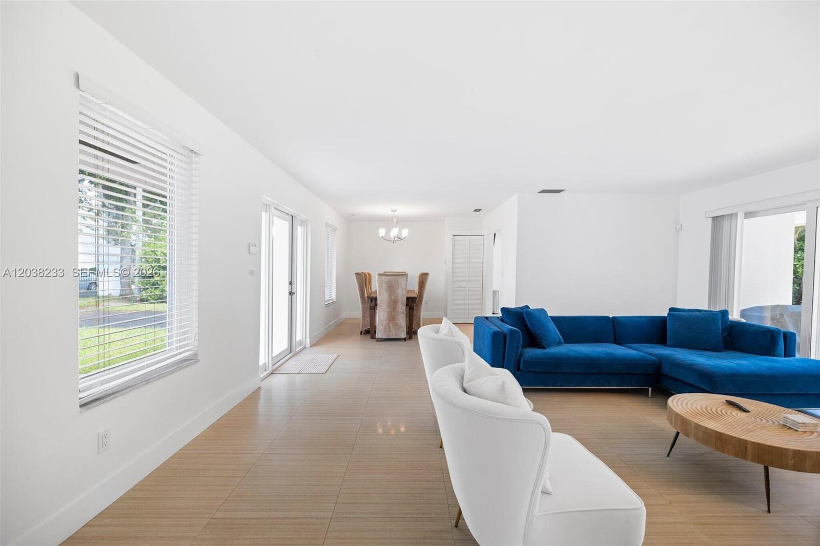 A bright living and dining area features white walls, tiled floors, and blue furniture — 811 Capri St, Coral Gables FL 33134, CORAL GABLES, FL