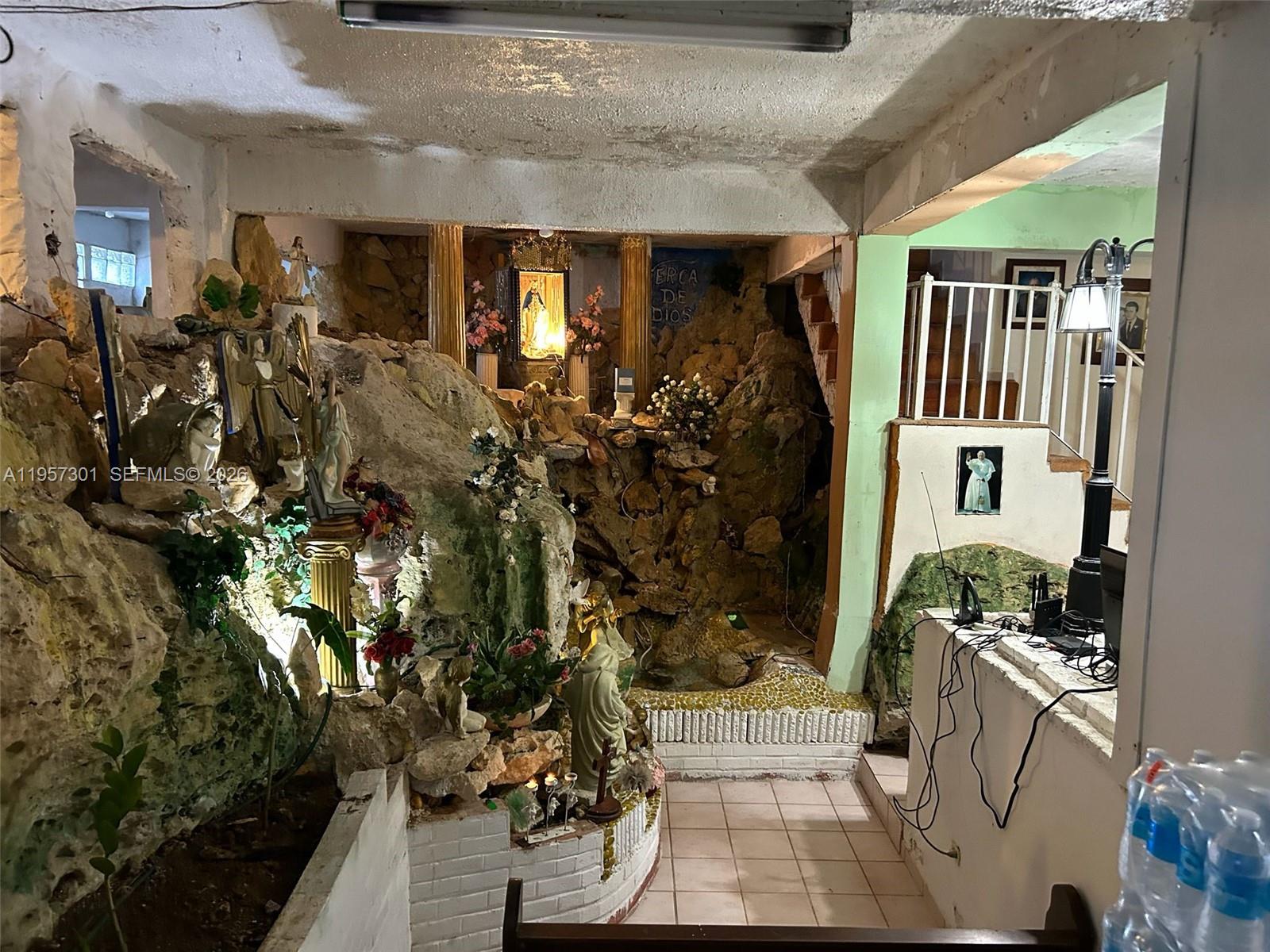 An indoor grotto with religious statues and rock formations sits beside a tiled staircase — 262 W Cruz de Malta, PR 00685, PR
