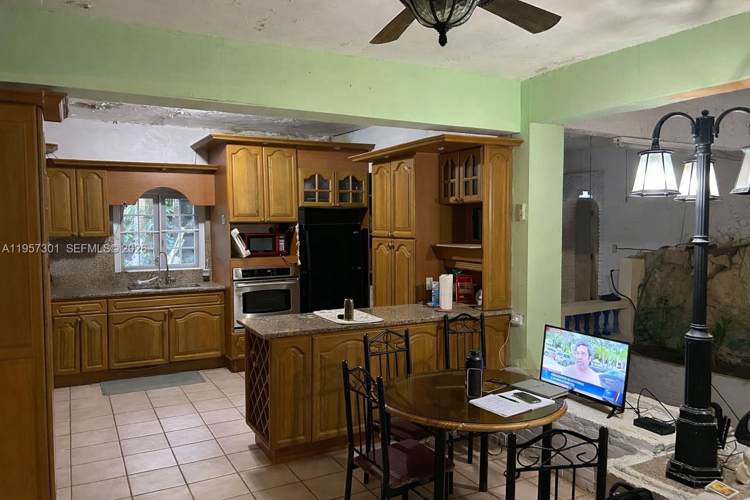 A kitchen with wooden cabinets, a granite island, and a dining table sits next to a patio — 262 W Cruz de Malta, PR 00685, PR