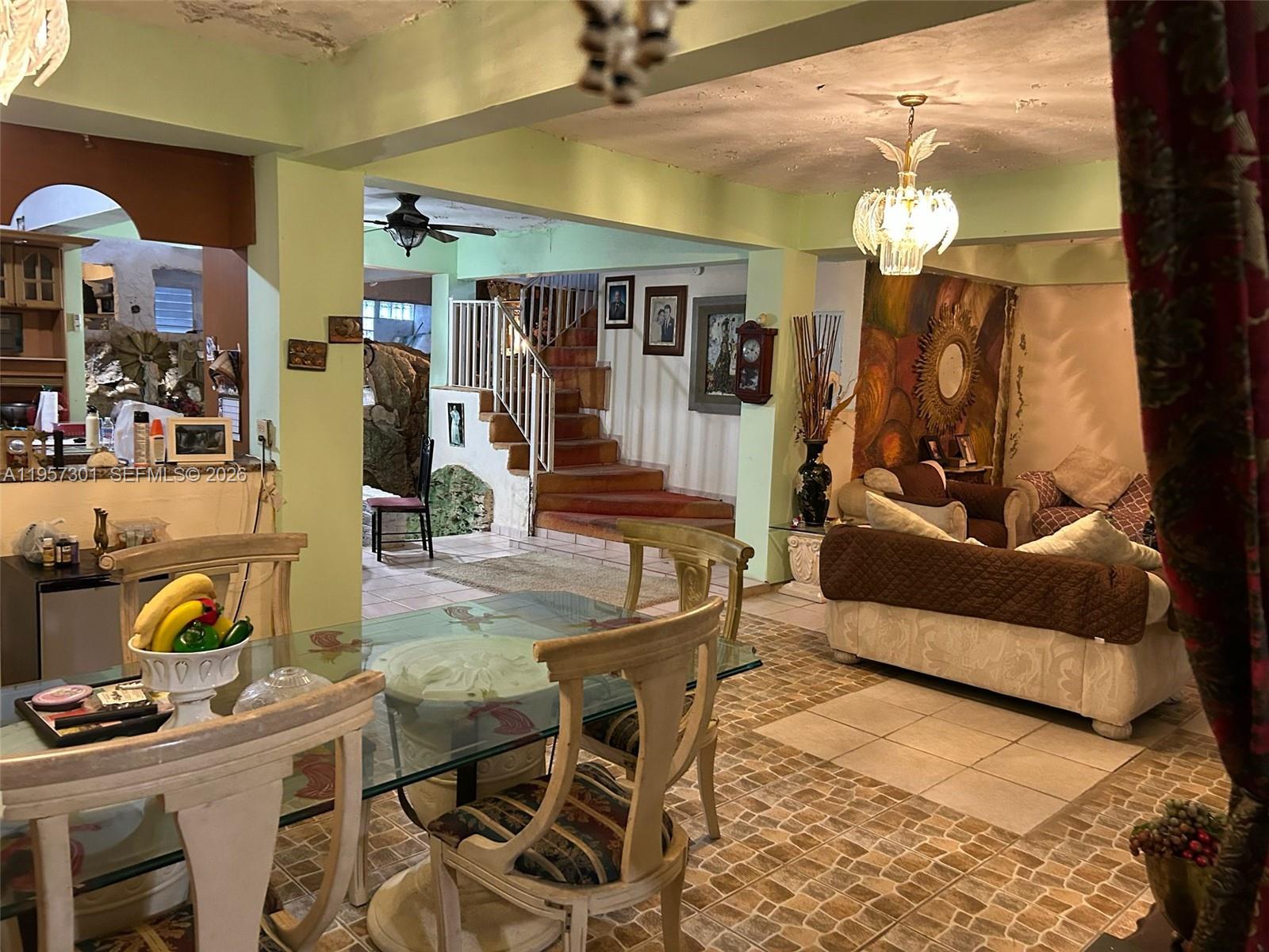 A dining area with a glass table opens into a living room featuring a staircase — 262 W Cruz de Malta, PR 00685, PR