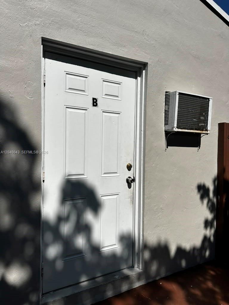 A white exterior door labeled B sits next to a window air conditioning unit — 1201 NE 148th St # B, Miami FL 33161, MIAMI, FL
