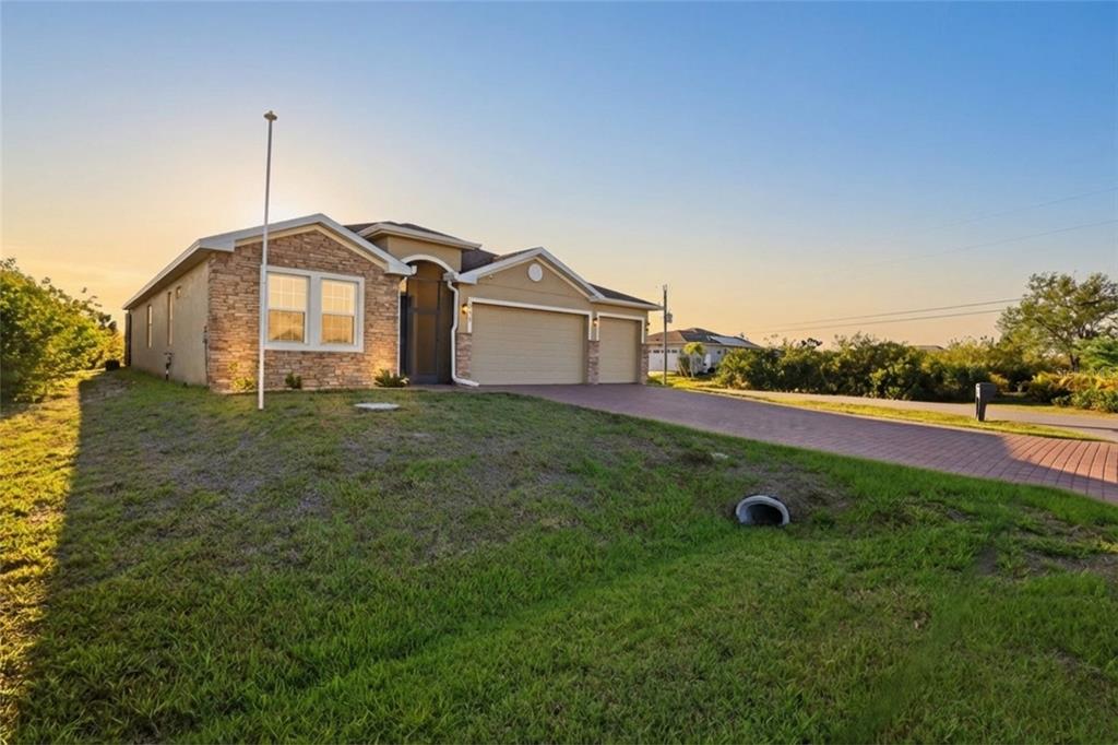 A single-story house with a stone facade, a three-car garage, and a paved driveway — 14879 WICHITA ROAD, PORT CHARLOTTE, FL