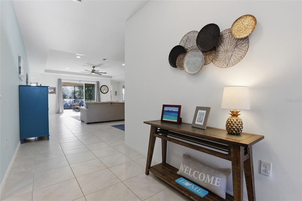 A bright entryway features a wooden console table, wall art, and tile flooring leading inside — 14879 WICHITA ROAD, PORT CHARLOTTE, FL