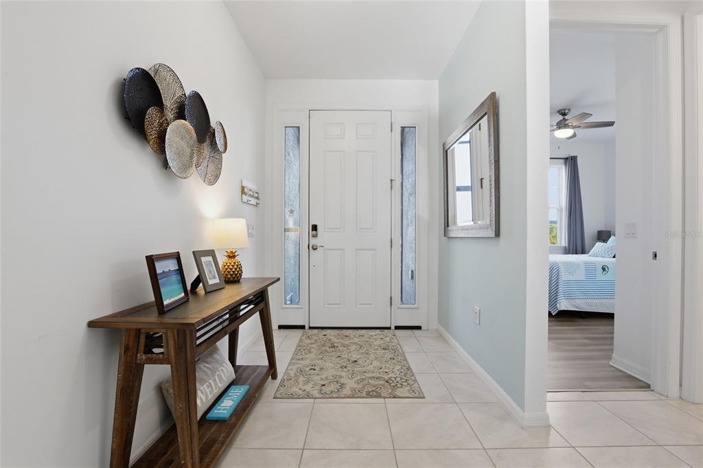 A bright entryway features a white front door, tile flooring, and a wooden console table — 14879 WICHITA ROAD, PORT CHARLOTTE, FL