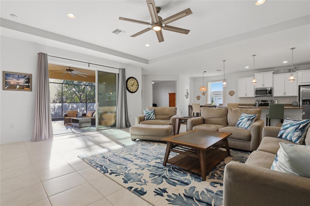 A living room with tile floors, a patterned area rug, and sliding doors to a patio — 14879 WICHITA ROAD, PORT CHARLOTTE, FL