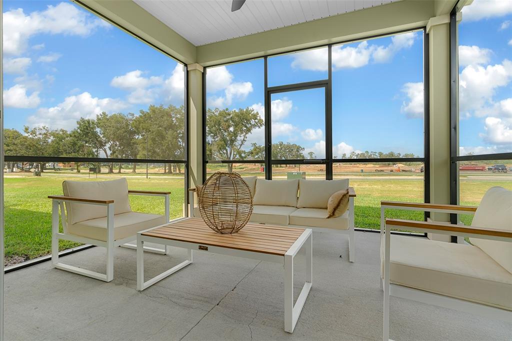 A screened-in patio features white metal furniture, a wood-slat coffee table, and a concrete floor — 8772 SW 67TH CIRCLE, OCALA, FL