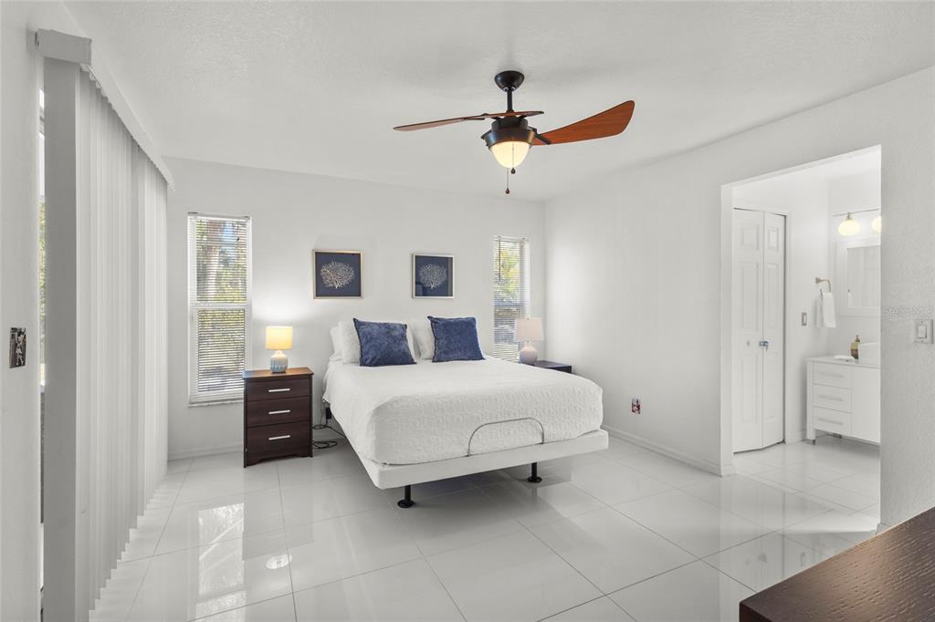 A bedroom with white walls, tile floors, a ceiling fan, and an attached bathroom — 3620 CANDIA AVENUE, NORTH PORT, FL
