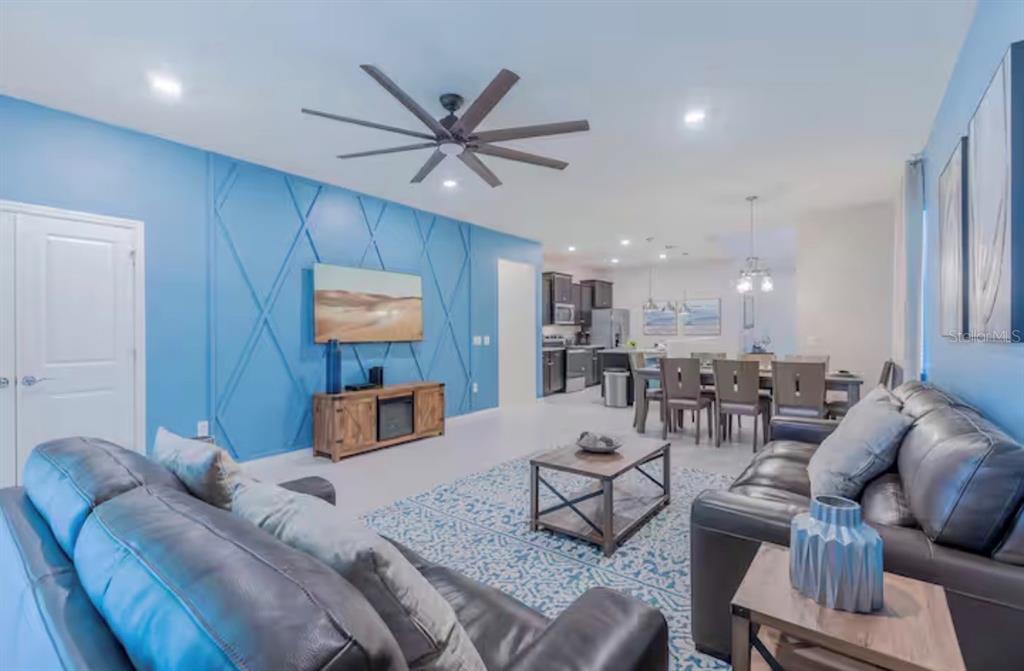 A living room with a blue accent wall, dark leather sofas, and an open kitchen — 2226 LELANI CIRCLE, DAVENPORT, FL