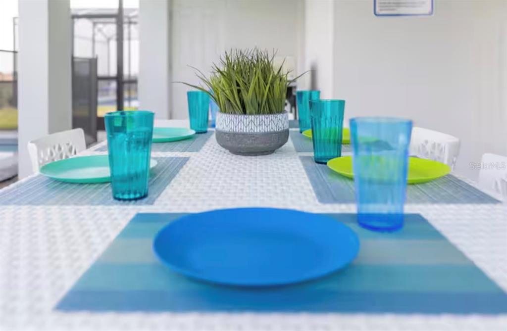 A dining table is set with blue plates, green plates, and blue plastic tumblers — 2226 LELANI CIRCLE, DAVENPORT, FL