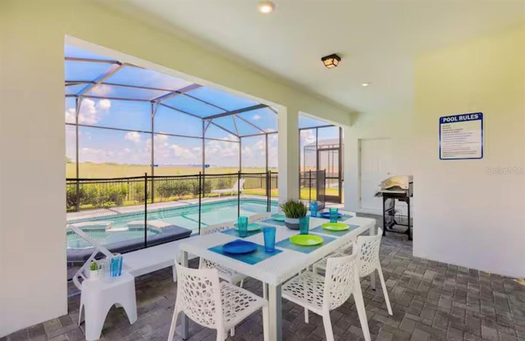 A covered patio features a dining table, a grill, and a screened-in swimming pool area — 2226 LELANI CIRCLE, DAVENPORT, FL