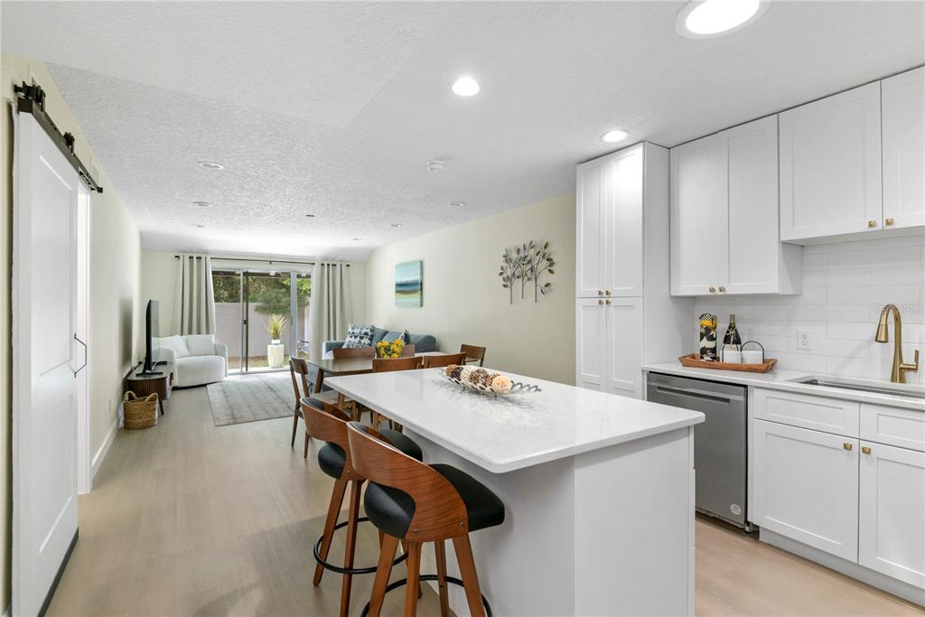 A kitchen with a white island and stools opens into a living area with sliding doors — 894 JONATHAN WAY UNIT 3B, ALTAMONTE SPRINGS, FL