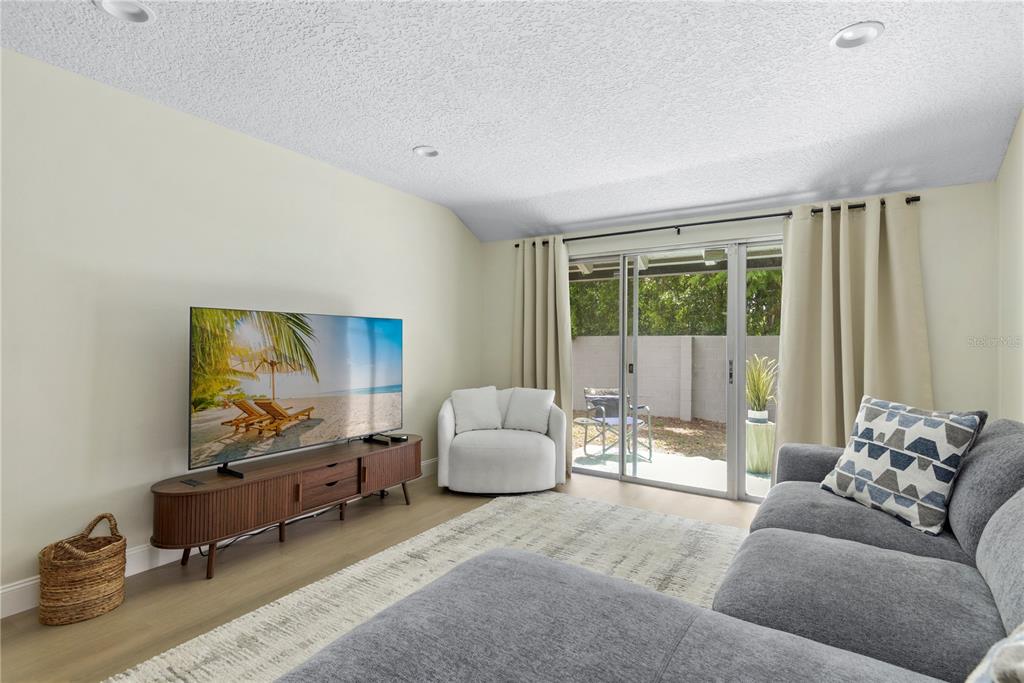 A living room features a television on a wooden console, a sectional sofa, and sliding doors — 894 JONATHAN WAY UNIT 3B, ALTAMONTE SPRINGS, FL