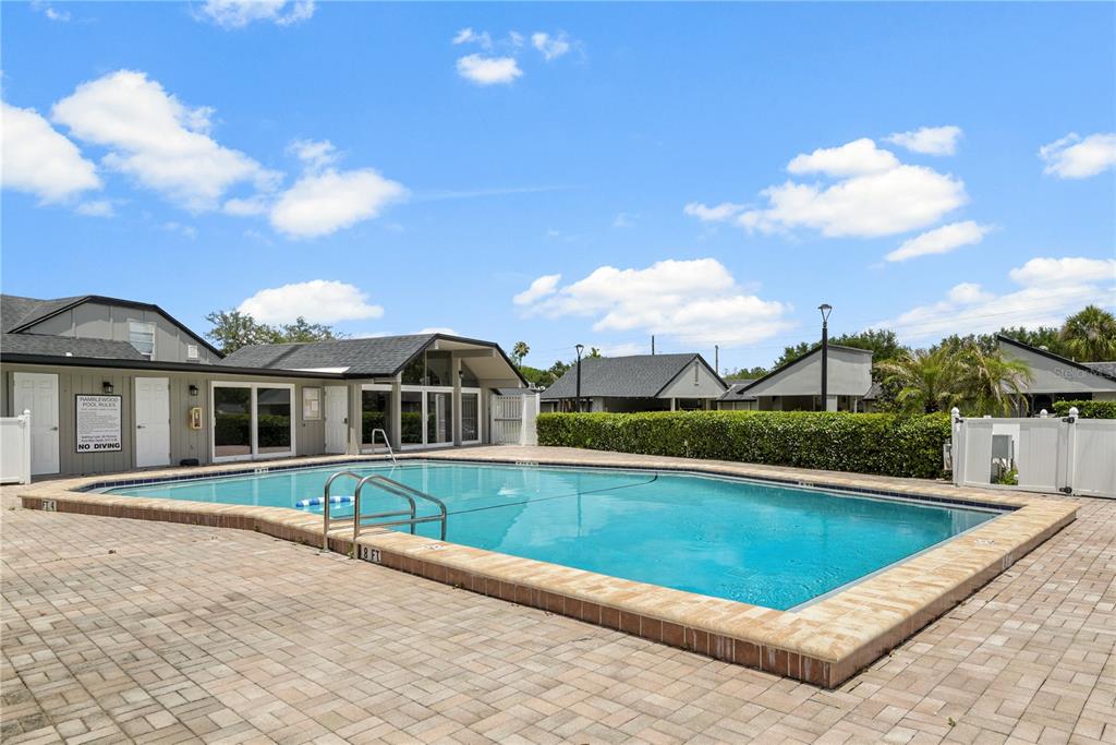 An outdoor swimming pool with a brick paver deck and a nearby clubhouse building — 894 JONATHAN WAY UNIT 3B, ALTAMONTE SPRINGS, FL