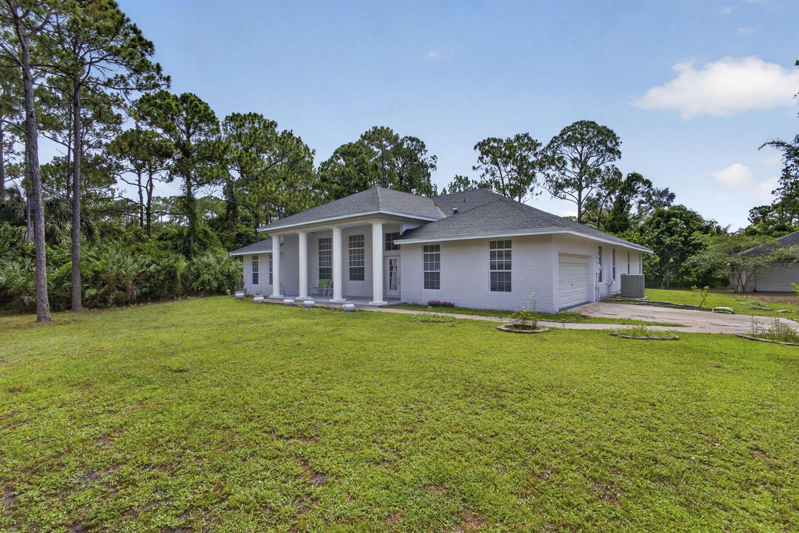 A white, single-story house with a columned front porch sits on a grassy lot — 16571 78th Road N, FL 33470, FL