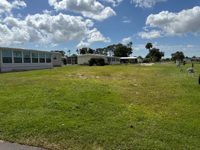 A vacant grassy lot sits between two manufactured homes under a partly cloudy sky — 412 MADONNA, NORTH PORT, FL