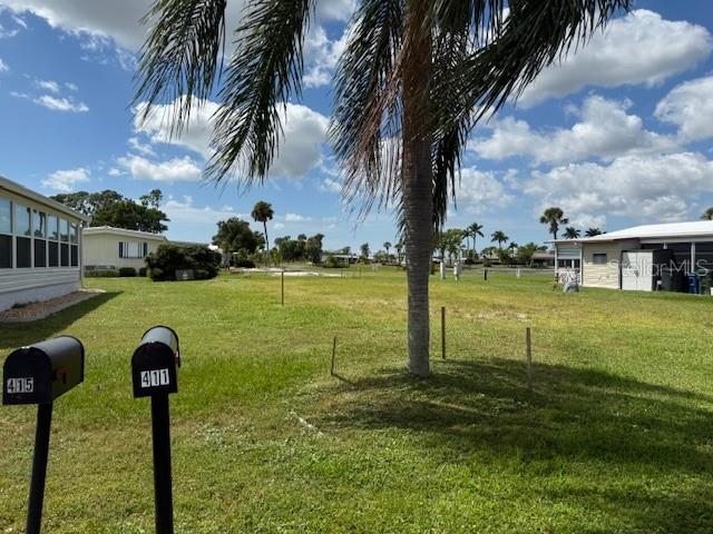 A grassy vacant lot sits between two mobile homes under a blue sky — 412 MADONNA, NORTH PORT, FL