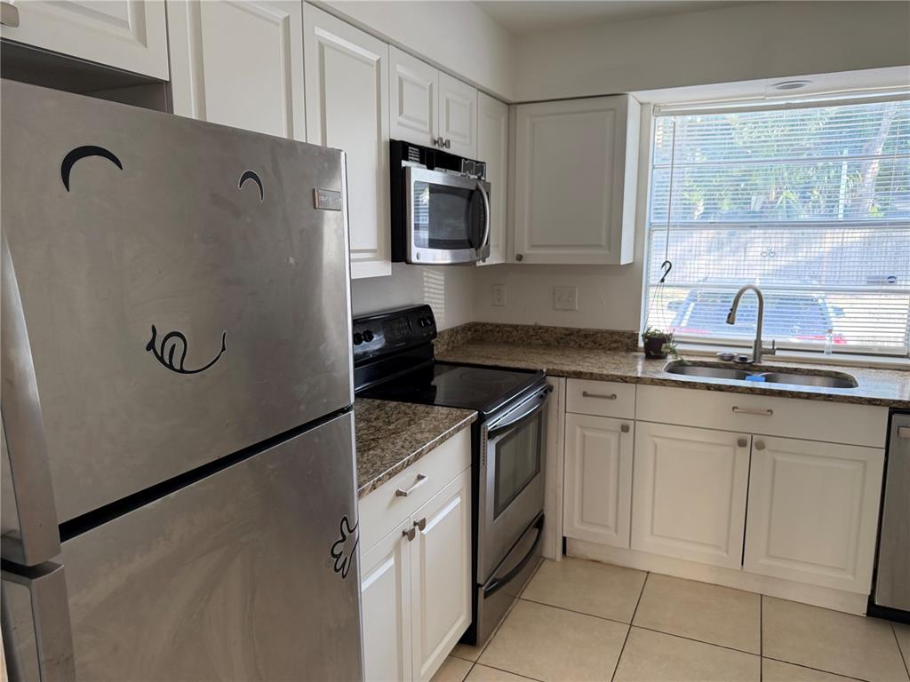 A kitchen features white cabinets, granite countertops, stainless steel appliances, and a window above the sink — 7513 ABONADO RD UNIT 7513, TAMPA, FL
