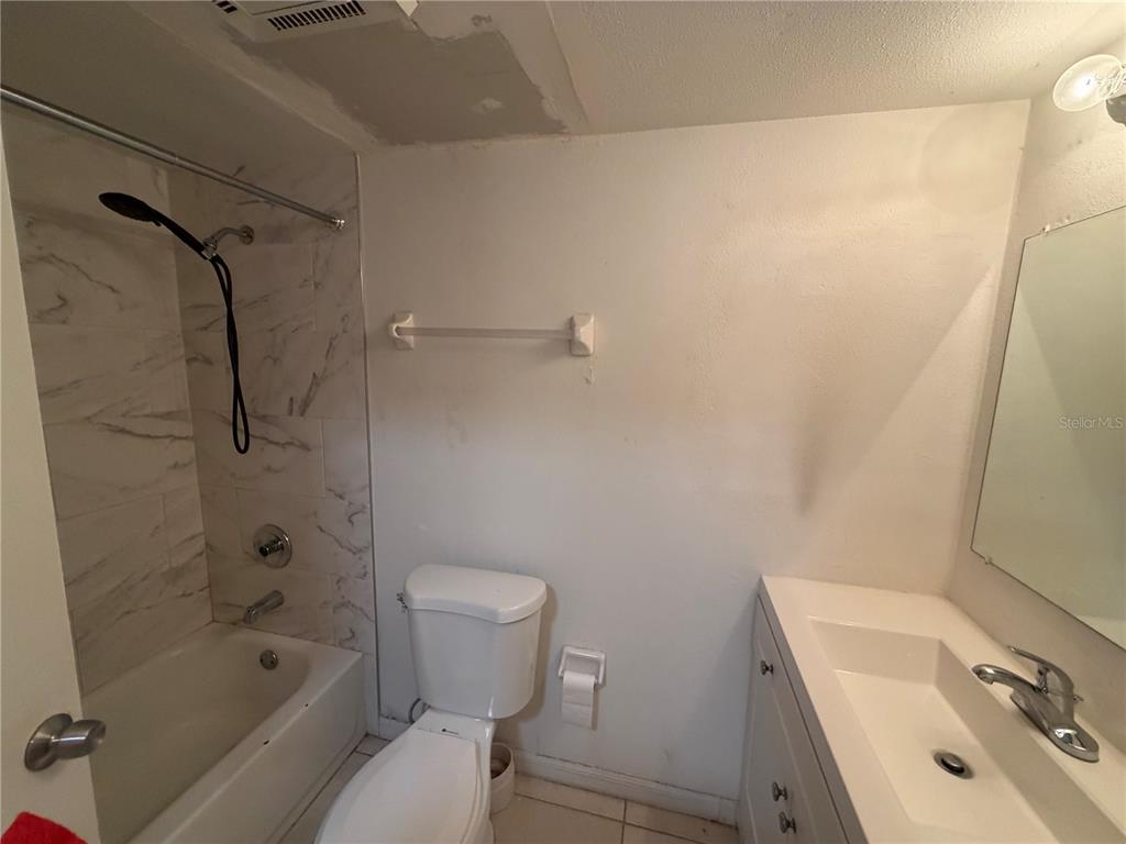 A bathroom features a white vanity, a toilet, and a shower-tub combo with marble-look tiles — 7513 ABONADO RD UNIT 7513, TAMPA, FL