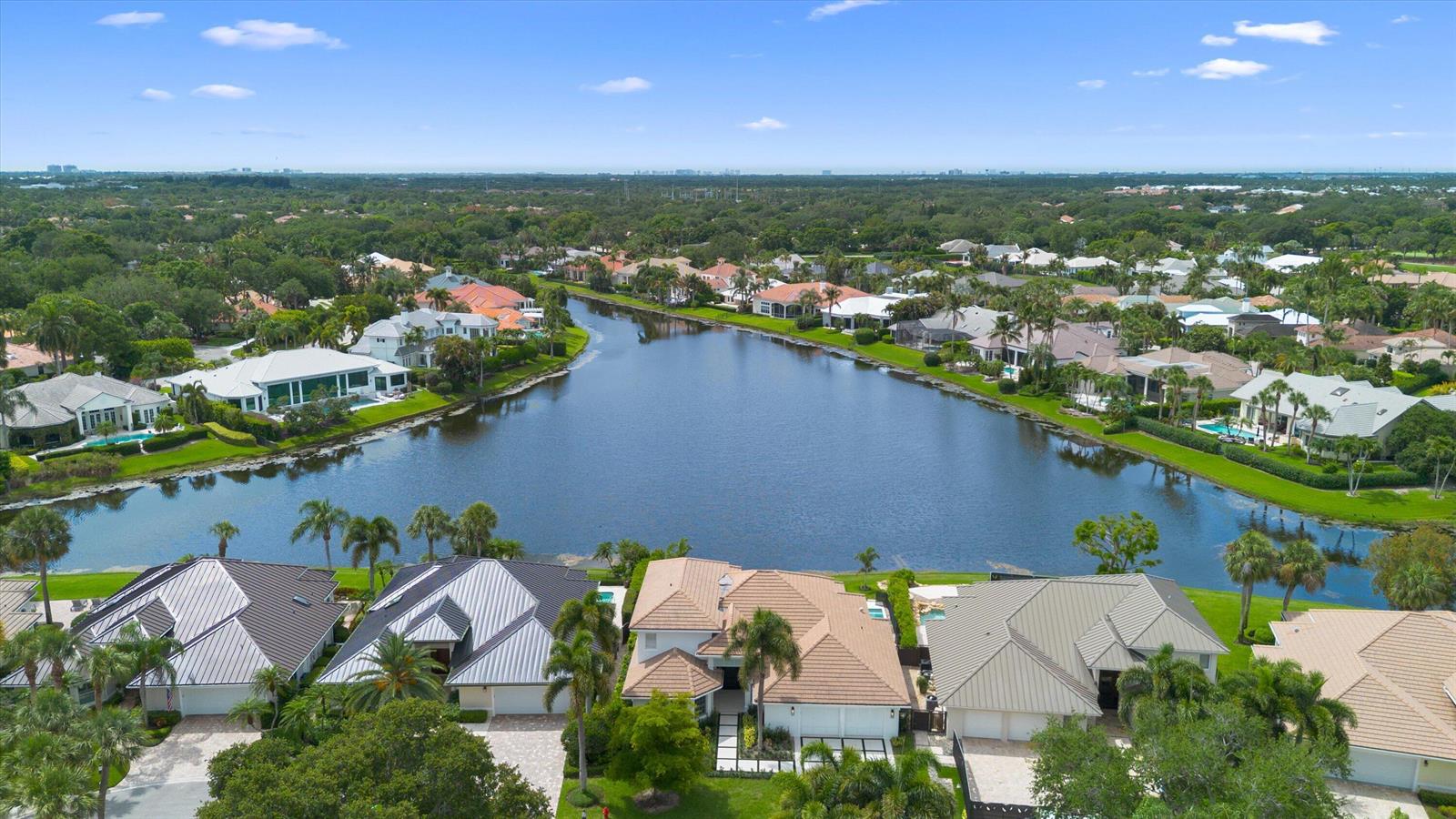 An aerial view shows a row of houses along a lake in a suburban neighborhood — 204 Birkdale Lane, Jupiter FL 33458, JUPITER, FL