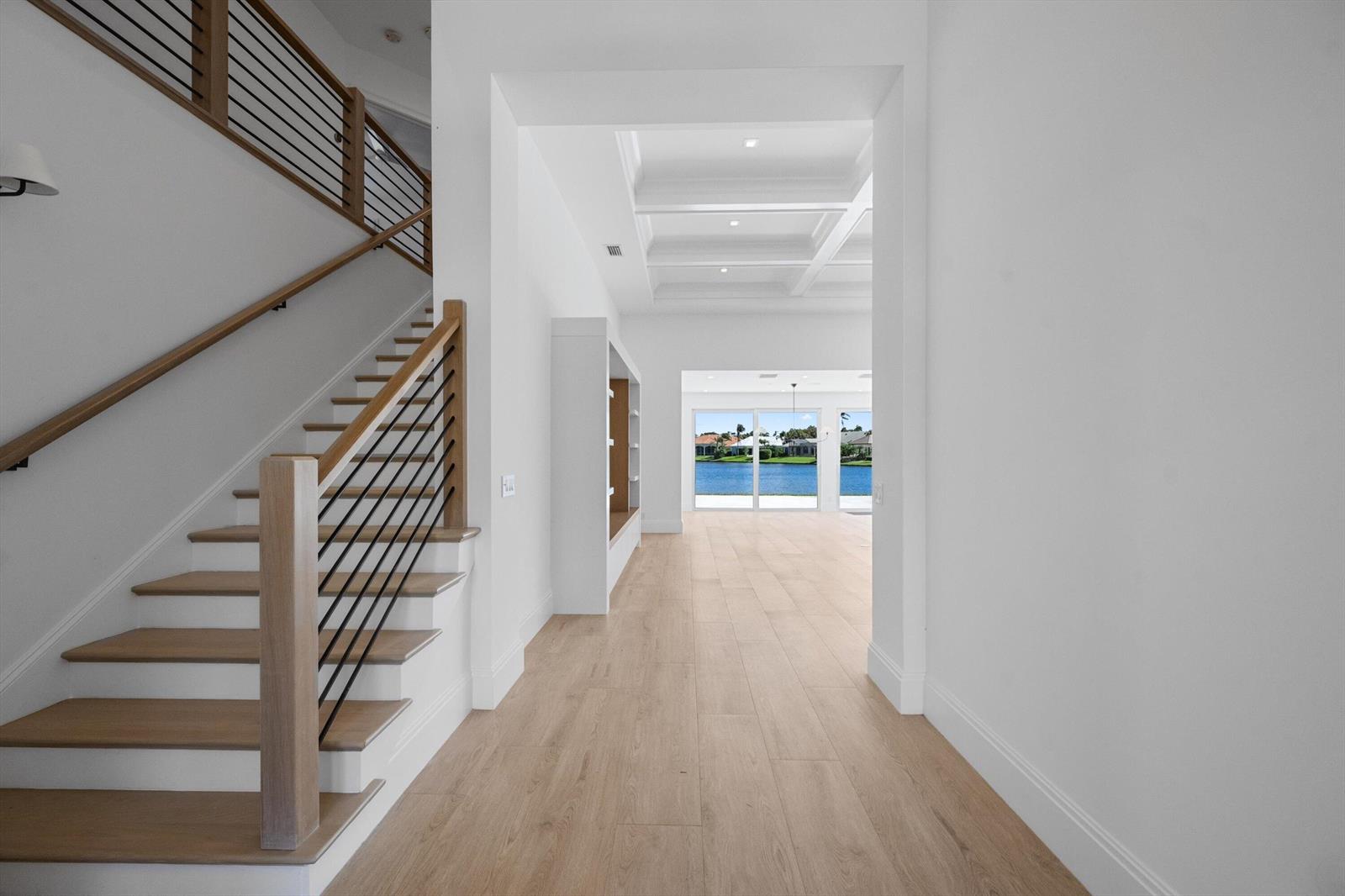 A bright foyer features light wood flooring, a staircase with metal railings, and a water view — 204 Birkdale Lane, Jupiter FL 33458, JUPITER, FL