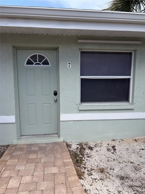 The exterior of a light green building features a front door with a small window — 9030 BLIND PASS ROAD UNIT C7, ST PETERSBURG, FL