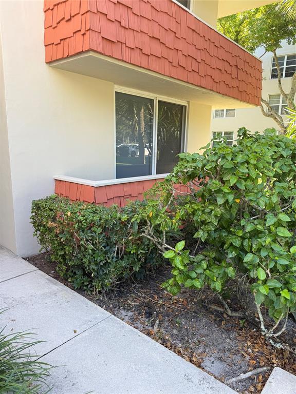 A ground-floor patio with a sliding glass door sits beneath a red-shingled balcony overhang — 4031 N Cypress Drive # 101, Pompano Beach FL 33069, POMPANO BEACH, FL