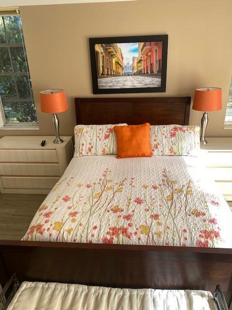 A bedroom features a wooden bed frame, floral bedding, orange accent pillows, and matching bedside lamps — 4031 N Cypress Drive # 101, Pompano Beach FL 33069, POMPANO BEACH, FL