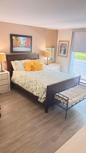 A bedroom features a dark wood bed frame, floral bedding, yellow pillows, and tile flooring — 4031 N Cypress Drive # 101, Pompano Beach FL 33069, POMPANO BEACH, FL