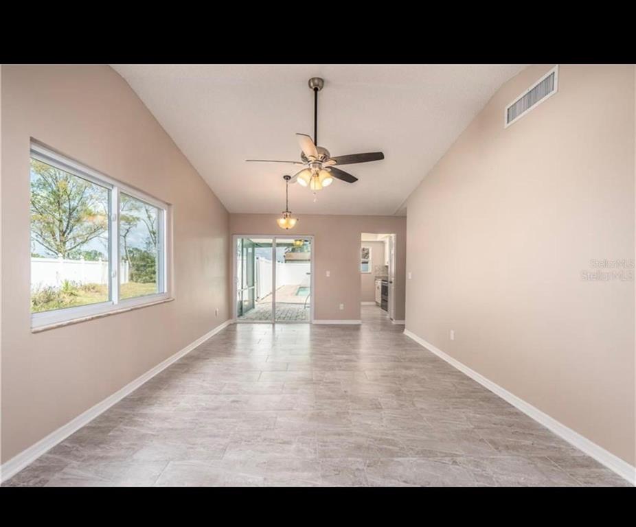 An empty room with light-colored walls, tile flooring, a ceiling fan, and sliding glass doors — 5409 SERENE LANE, ORLANDO, FL