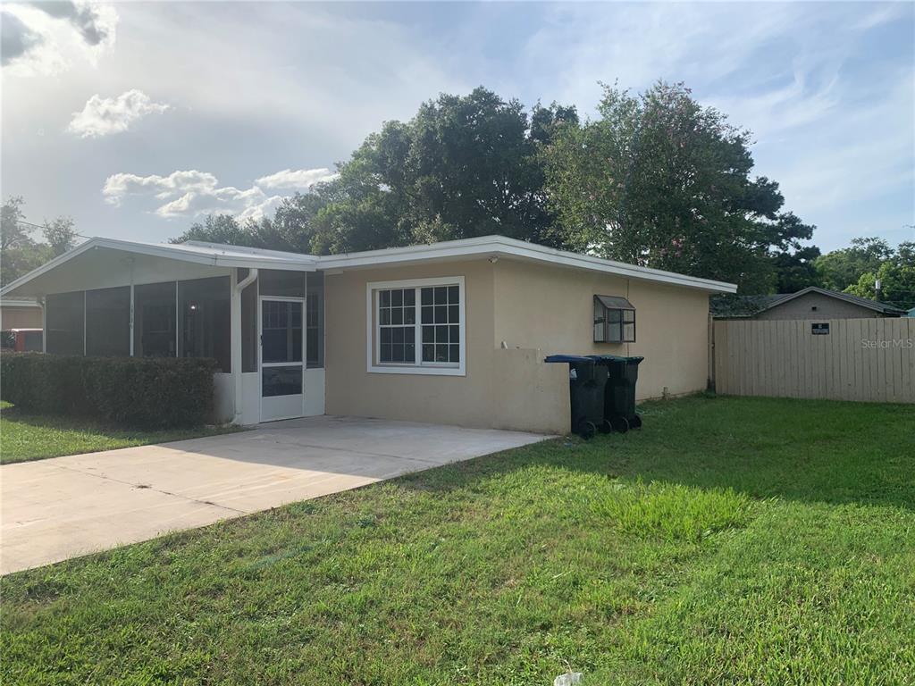 A single-story house with a screened-in porch, concrete driveway, and tan stucco exterior — 1915 WEEKS AVENUE, ORLANDO, FL