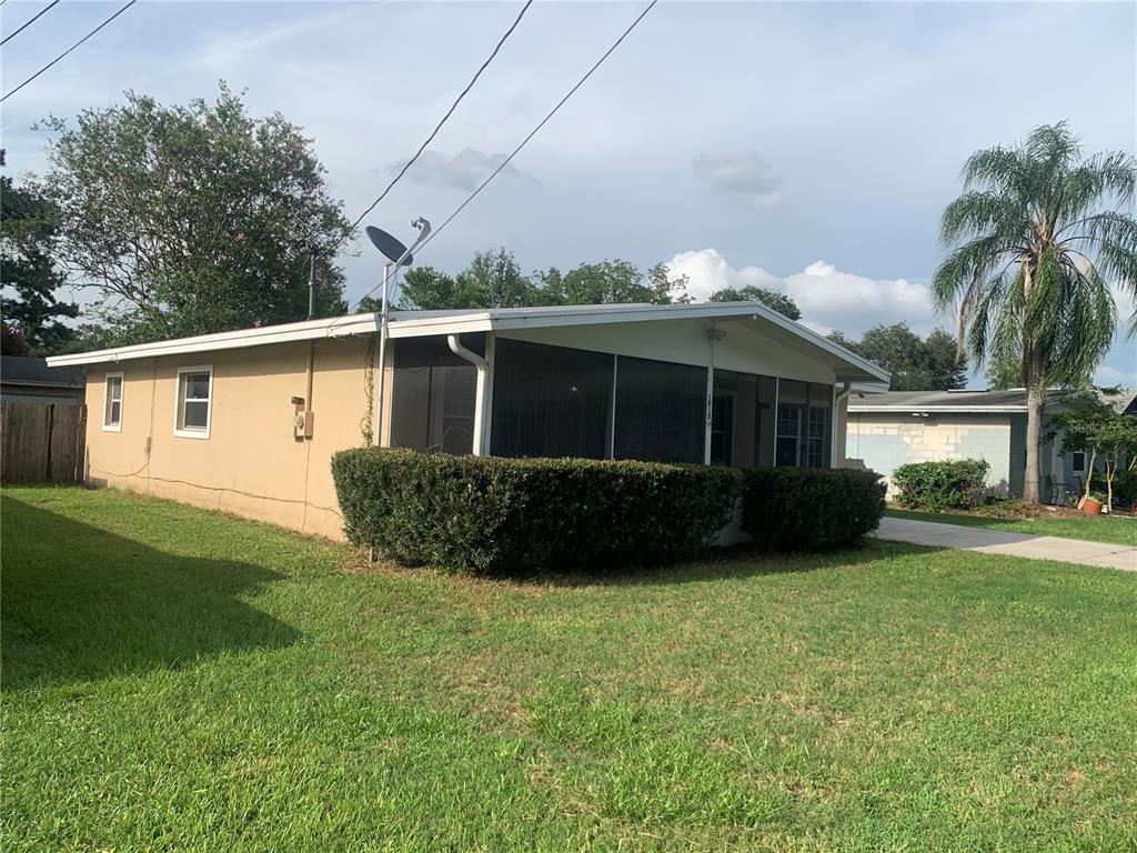 A single-story house with a screened-in front porch and a large hedge in the yard — 1915 WEEKS AVENUE, ORLANDO, FL