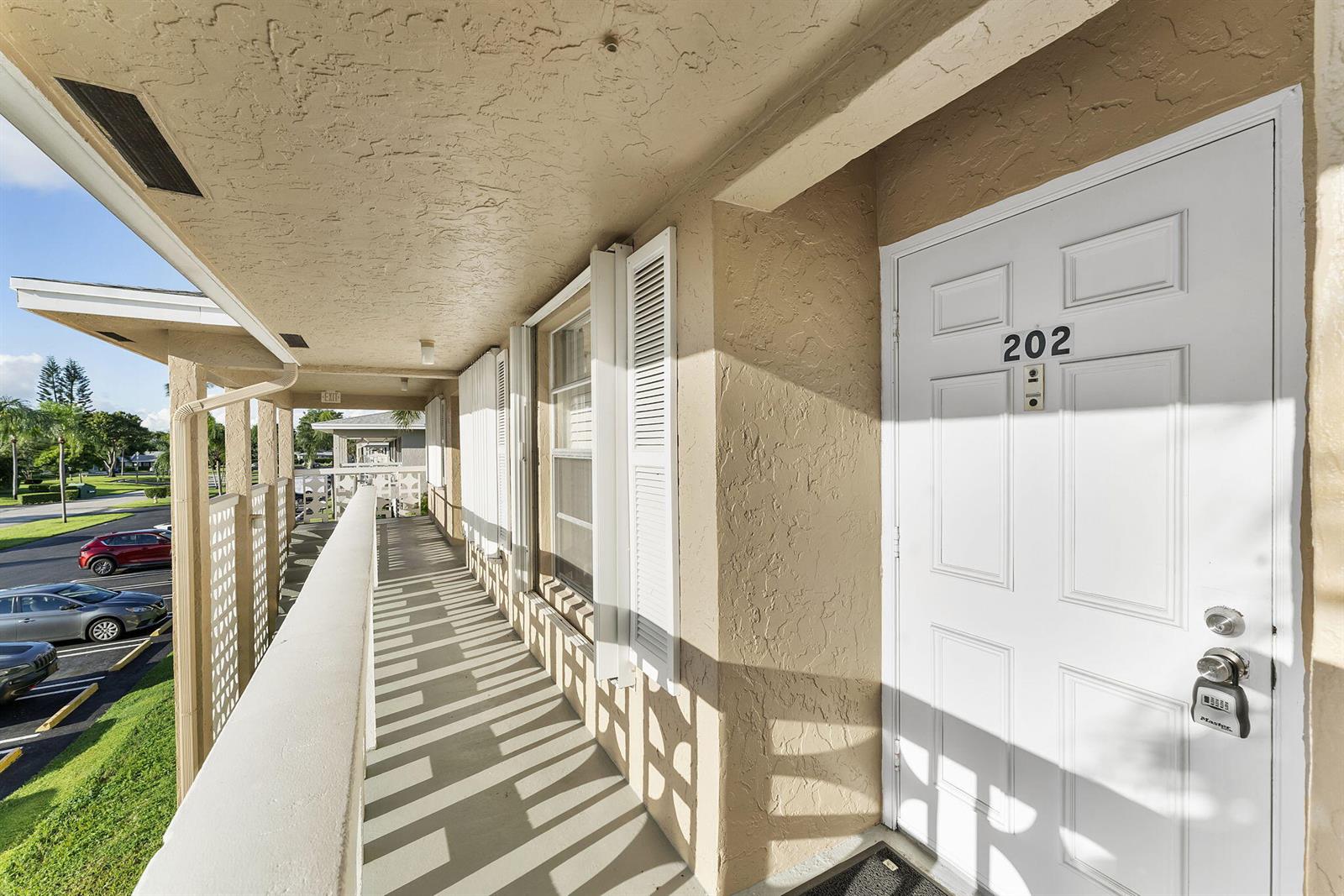 An exterior walkway leads to the white front door of apartment 202 — 1050 Citrus # 202, Delray Beach FL 33445, DELRAY BEACH, FL