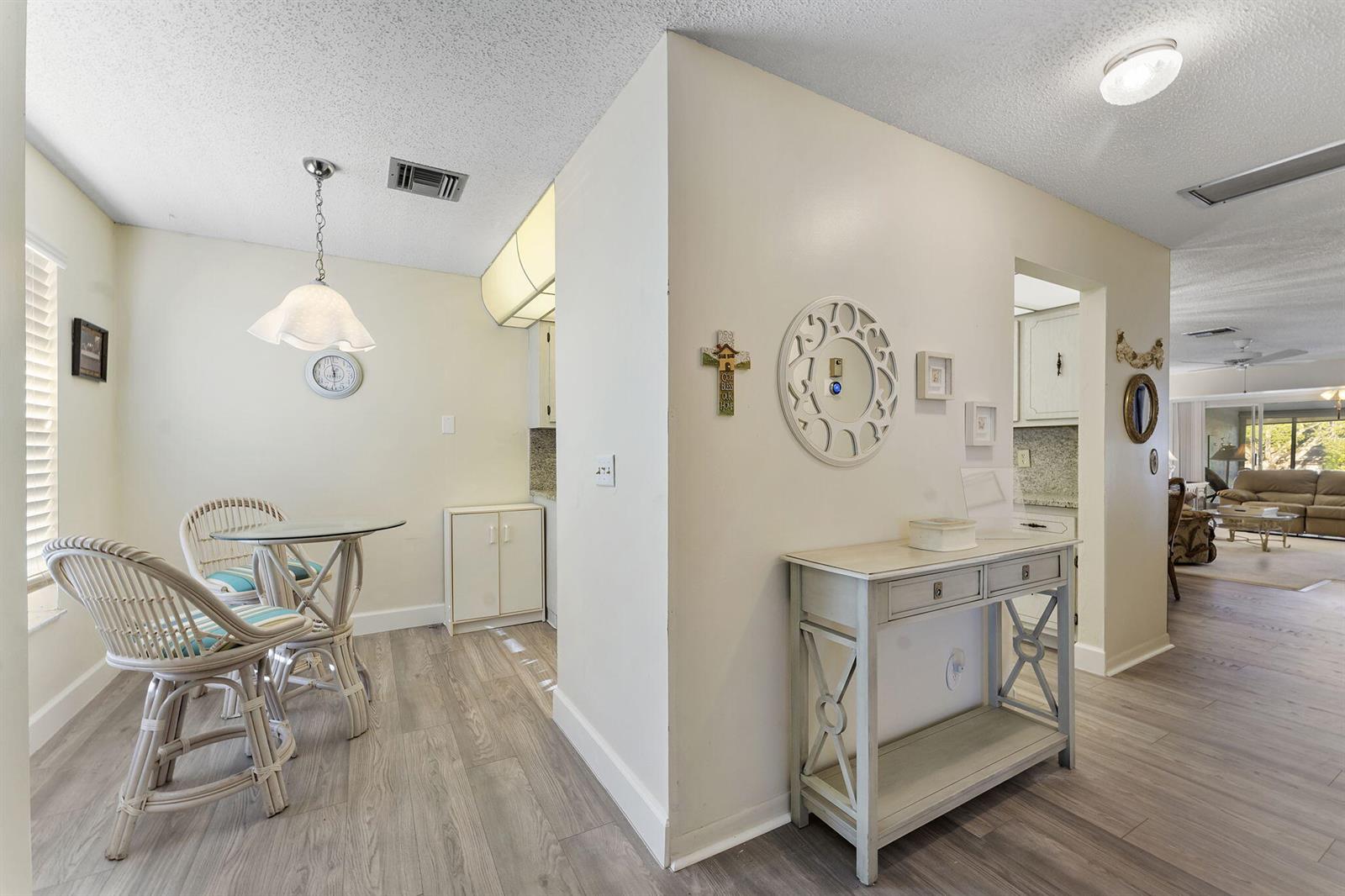 A dining area with wicker chairs and a console table sits beside a kitchen entrance — 1050 Citrus # 202, Delray Beach FL 33445, DELRAY BEACH, FL