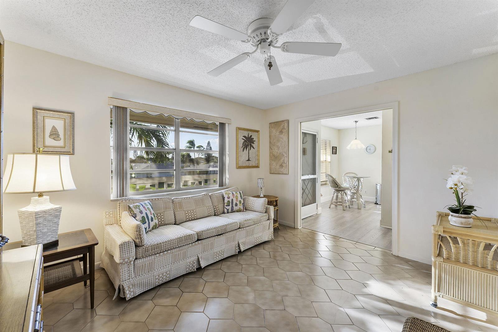 A living room with a patterned sofa, tile flooring, and a ceiling fan — 1050 Citrus # 202, Delray Beach FL 33445, DELRAY BEACH, FL