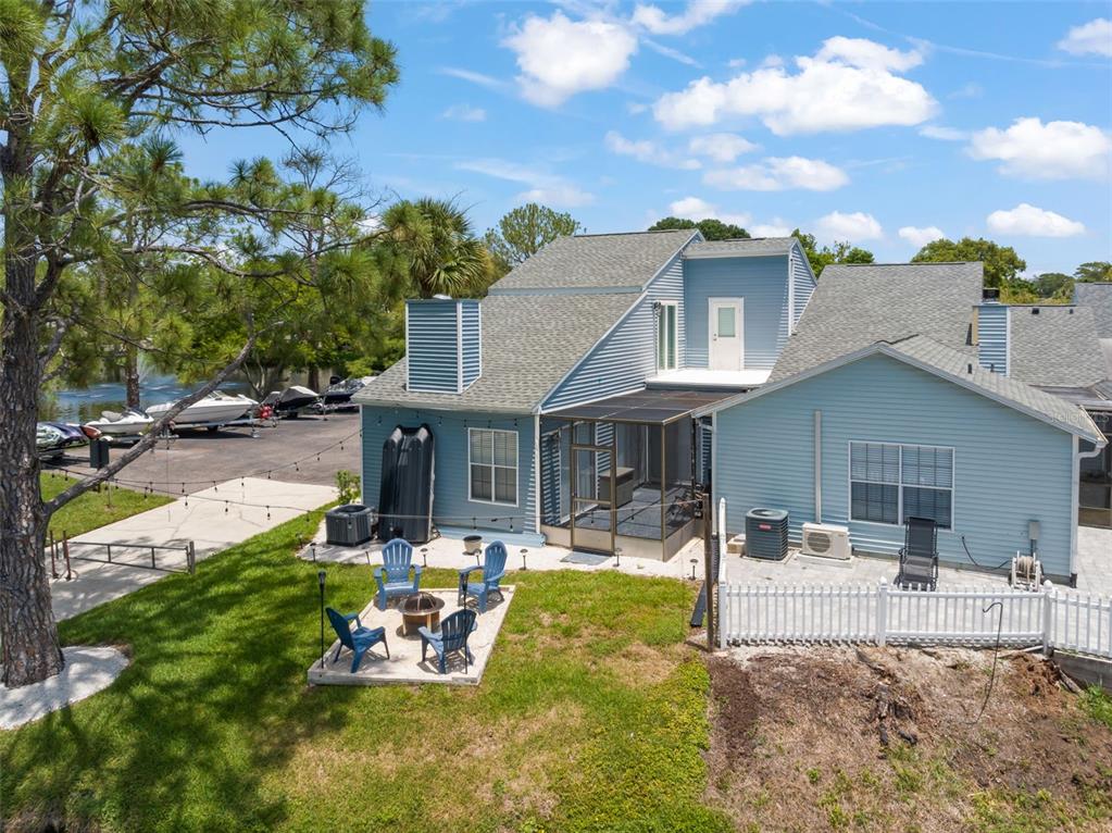 A light blue two-story house sits beside a pond with a patio and boat ramp — 872 BAY LAKE COURT, CASSELBERRY, FL