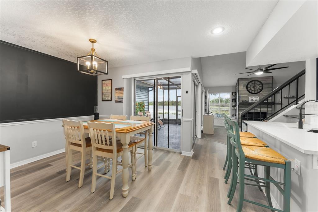 A dining area with a black accent wall, light wood flooring, and a sliding glass door — 872 BAY LAKE COURT, CASSELBERRY, FL