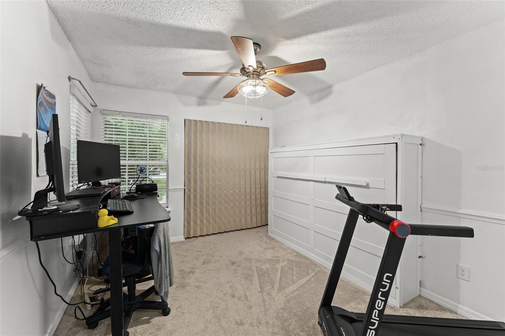A home office features a desk, a treadmill, and a white wall-mounted Murphy bed — 872 BAY LAKE COURT, CASSELBERRY, FL