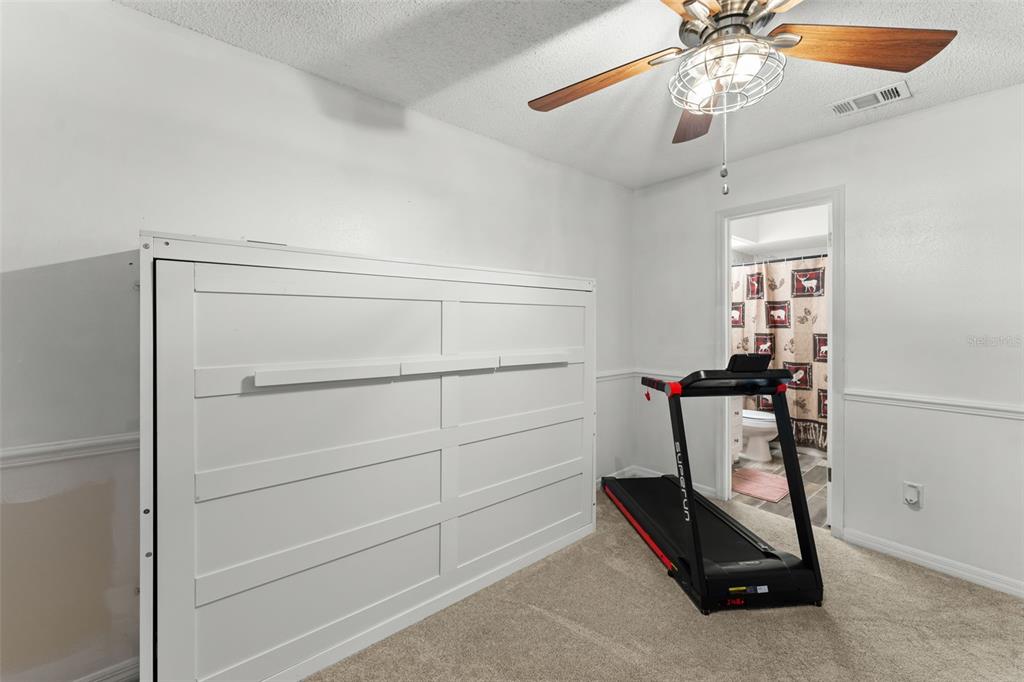 A room with a white Murphy bed, a treadmill, and an attached bathroom — 872 BAY LAKE COURT, CASSELBERRY, FL