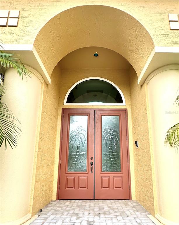 A yellow stucco home entrance features double doors with palm tree glass inserts — 17 PROMENADE AT LIONSPAW, DAYTONA BEACH, FL