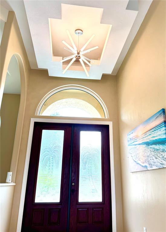 An entryway features a dark wood double door, a starburst chandelier, and a tray ceiling — 17 PROMENADE AT LIONSPAW, DAYTONA BEACH, FL