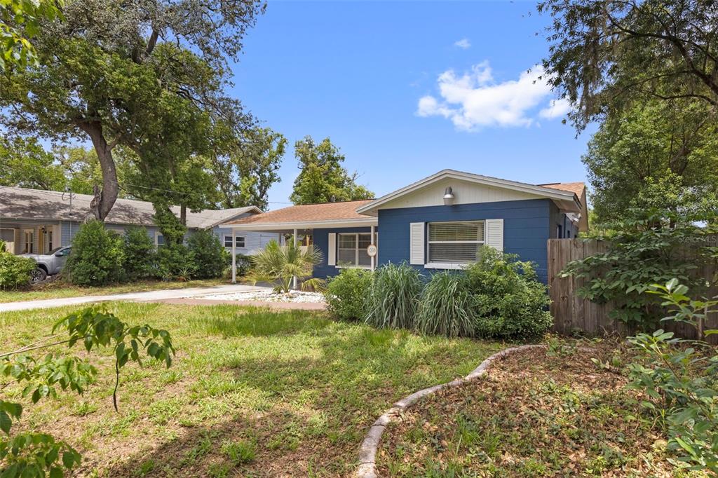 A blue single-story house with a carport and a front yard with trees — 1218 E NEW ORLEANS AVENUE, TAMPA, FL