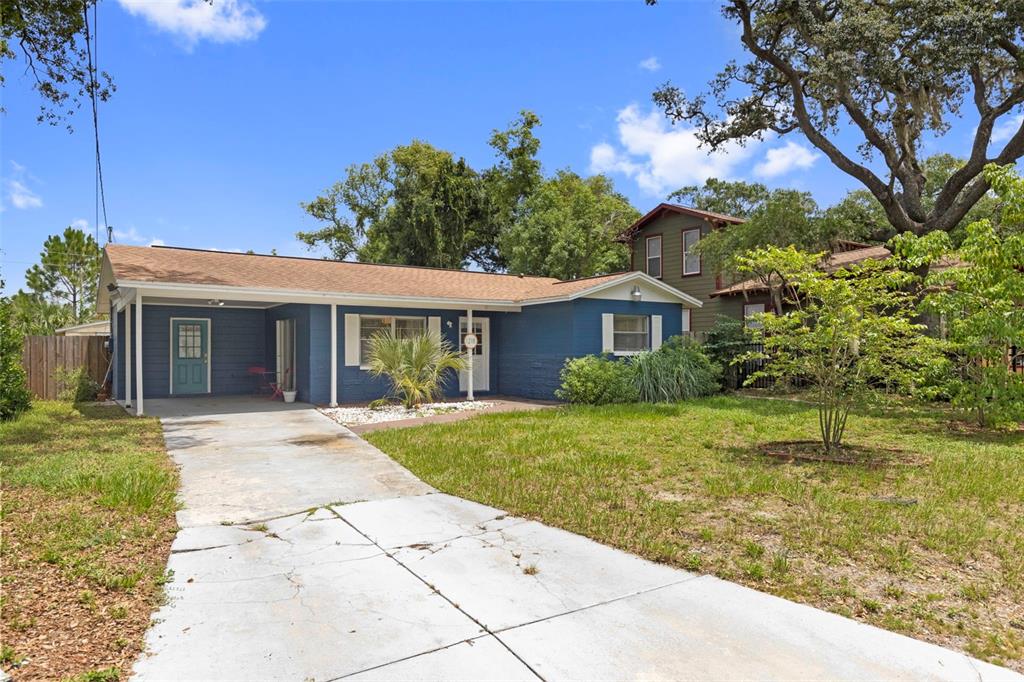 A blue single-story house features a covered carport, a concrete driveway, and a front lawn — 1218 E NEW ORLEANS AVENUE, TAMPA, FL