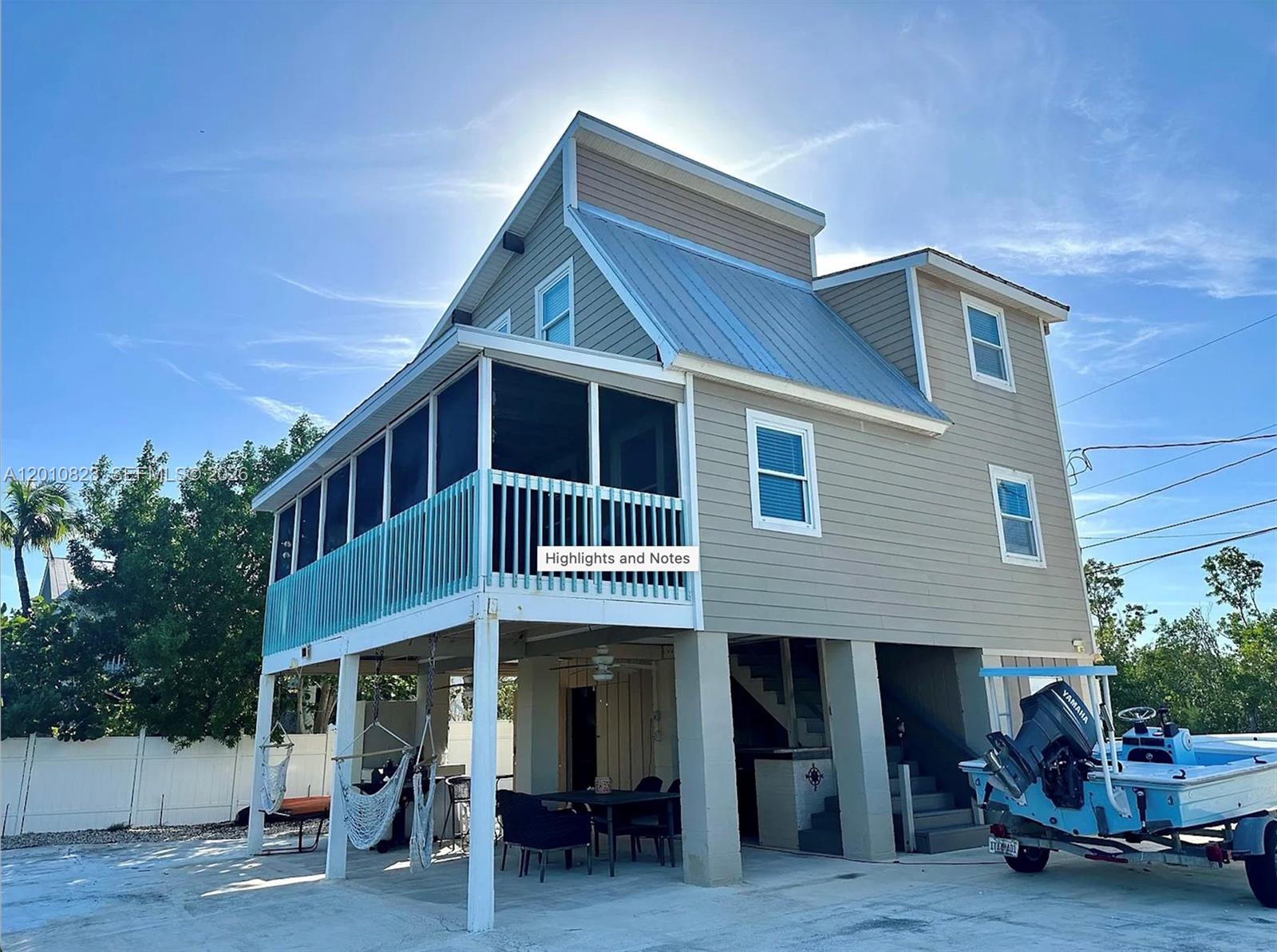 A two-story house on stilts features a screened porch, metal roof, and a boat parked underneath — 813 Hawksbill Ln, Sugarloaf FL 33042, SUGARLOAF, FL