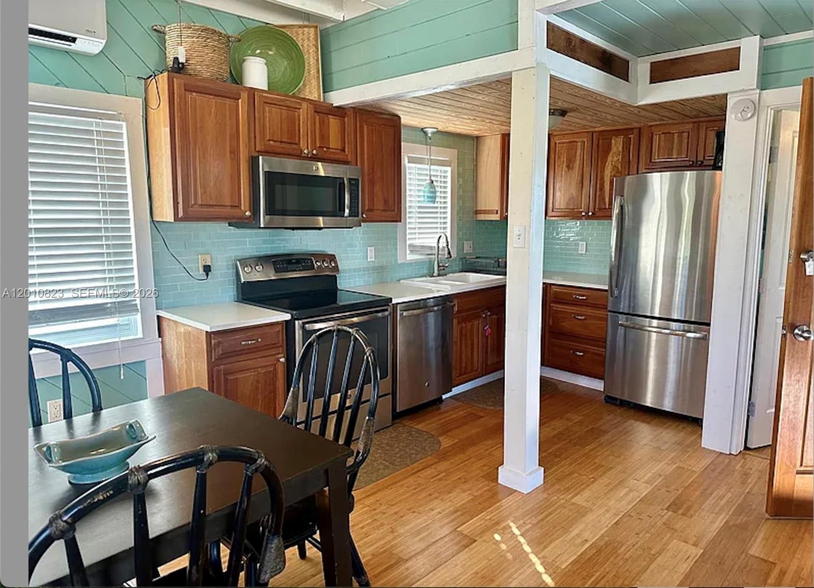 A kitchen features wood cabinets, stainless steel appliances, light blue tile backsplash, and hardwood floors — 813 Hawksbill Ln, Sugarloaf FL 33042, SUGARLOAF, FL
