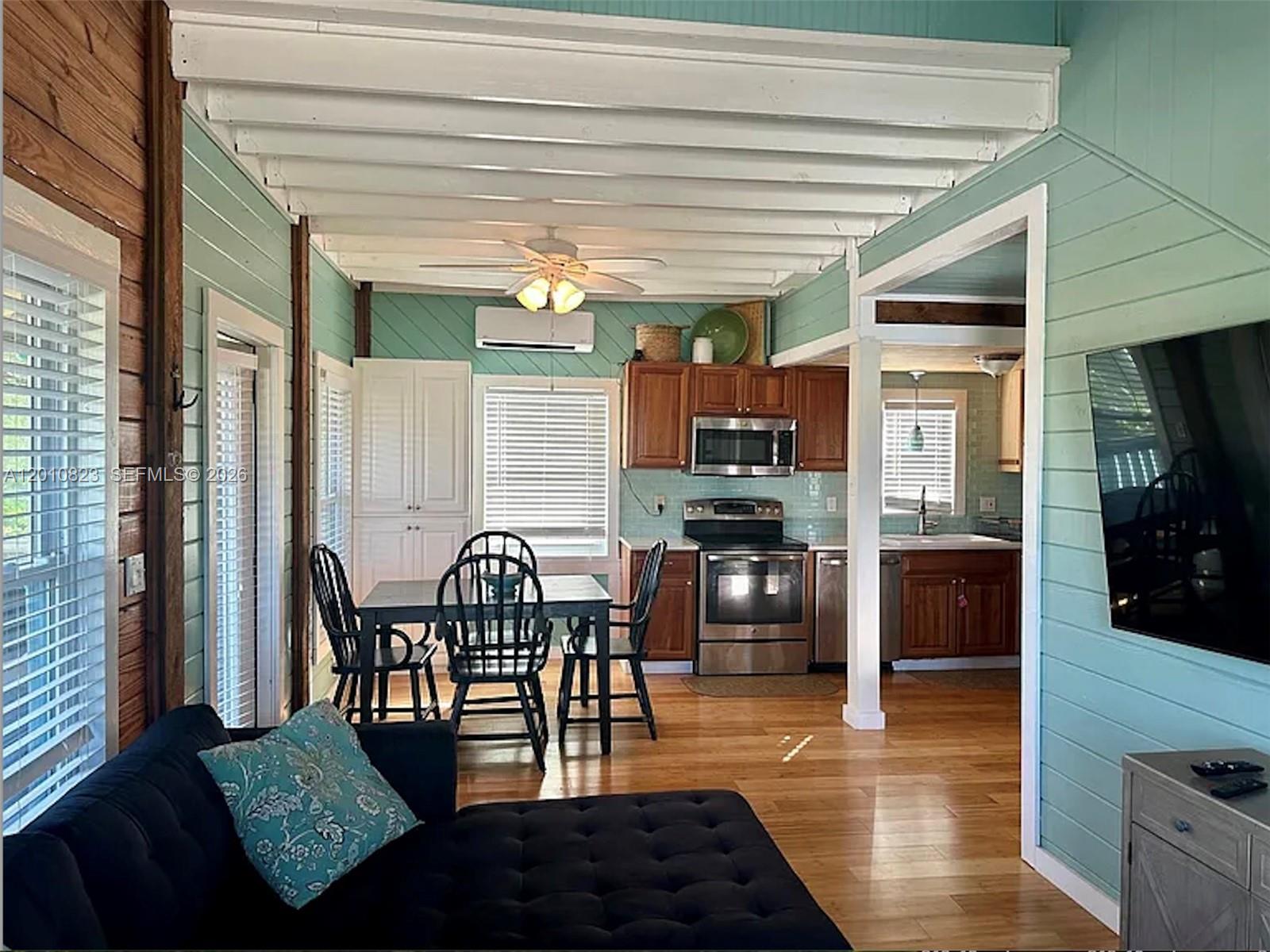 An open-concept kitchen and dining area features light blue walls, wood floors, and white beams — 813 Hawksbill Ln, Sugarloaf FL 33042, SUGARLOAF, FL