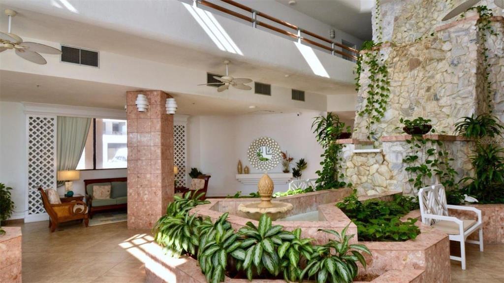 A lobby area features a stone fireplace, a central indoor fountain, and tiled flooring — 3023 S ATLANTIC AVENUE UNIT 903, DAYTONA BEACH, FL