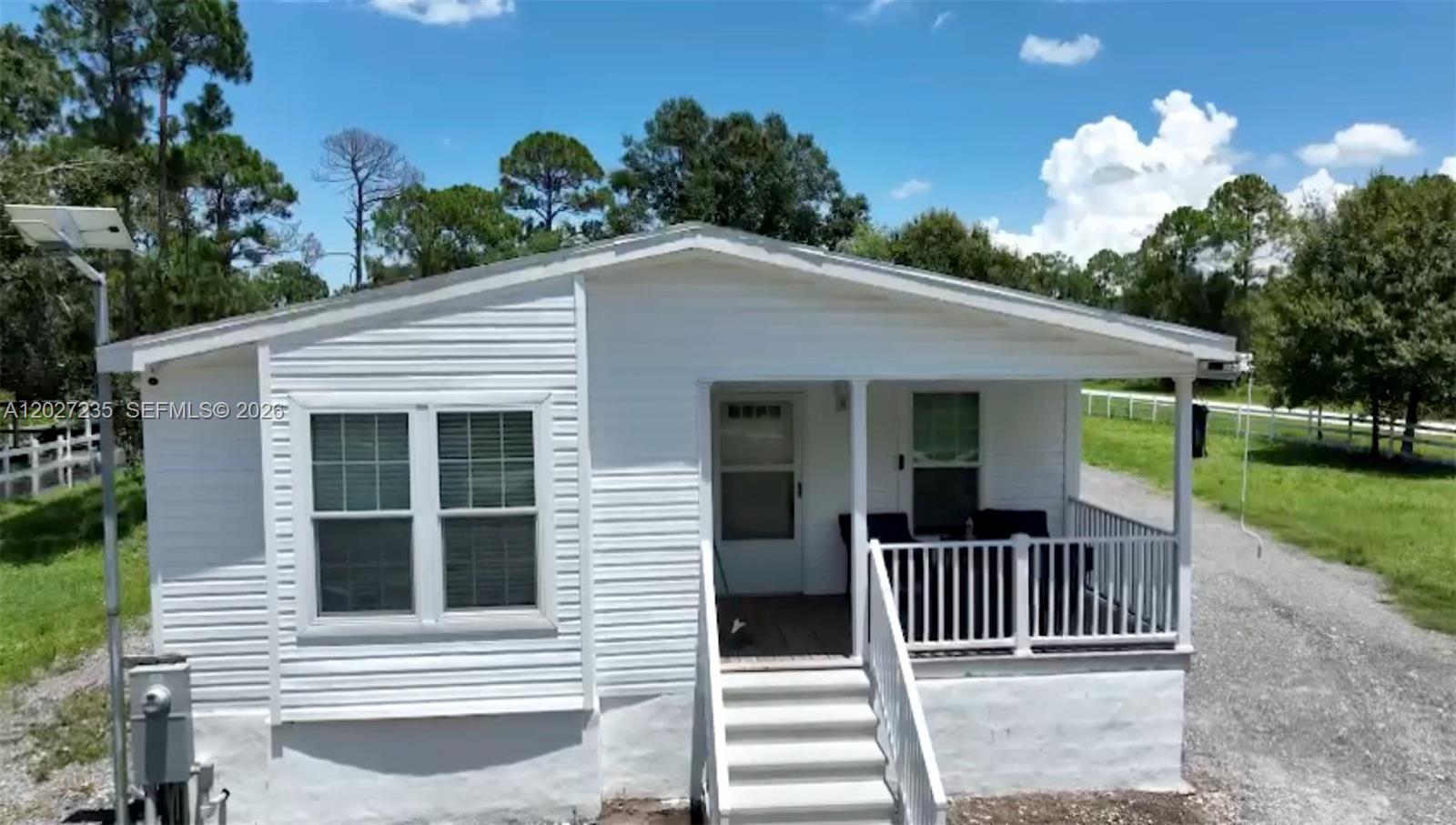 A white single-story house features a front porch with stairs and a gravel driveway — 725 N Willows St # 0, Clewiston FL 33440, CLEWISTON, FL