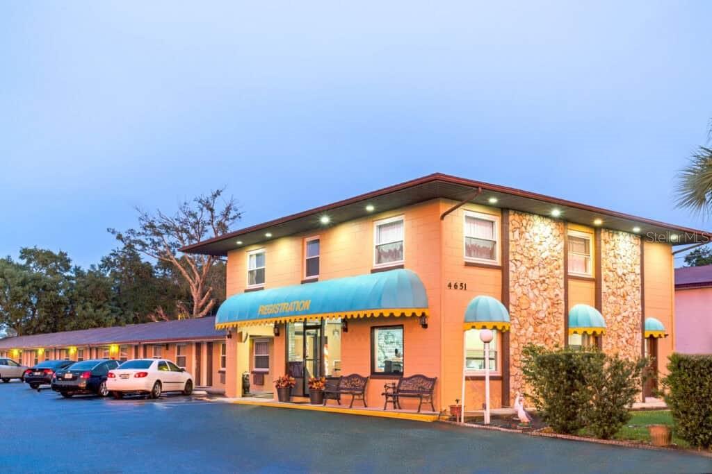 Exterior view of a two-story motel with a registration office and blue fabric awnings — 4651 W IRLO BRONSON MEMORIAL HIGHWAY, KISSIMMEE, FL